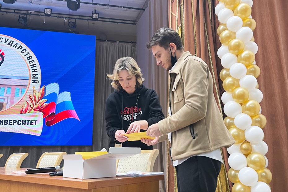 Адам Мякиев передает конверт с набором и документами Екатерине Кузнецовой 